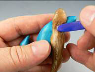 Blue clay being pressed onto clay branch